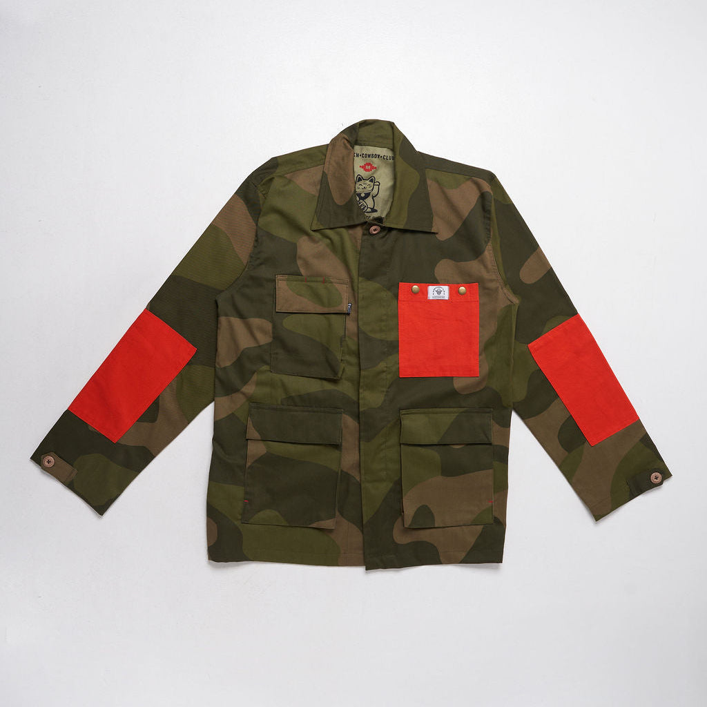 Camouflage jacket with red patches on a white background