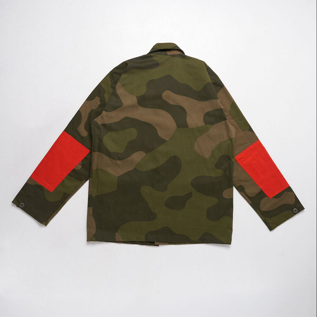 Camouflage jacket with red arm patches on a white background